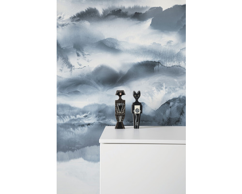 Decoratieve figuren op een witte kast voor een muur met een landschapspatroon.