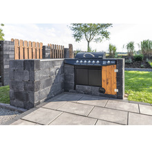 Buitenkeuken met barbecue, gebouwd van grijze betonstenen en houten elementen, in de tuin