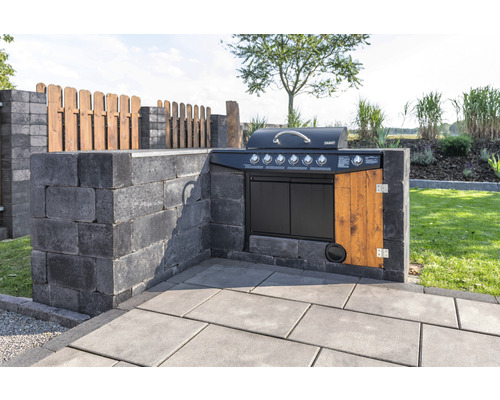 Buitenkeuken met barbecue, gebouwd van grijze betonstenen en houten elementen, in de tuin