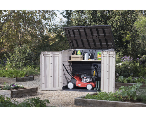 Tuinscene met een tuinkast met open deuren, grasmaaier en tuingereedschap