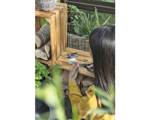 Vrouw snijdt touw door met een tuinschaar naast houten kisten en planten.
