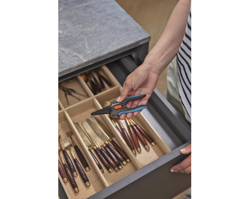 Iemand pakt een Gardena snoeischaar uit een lade met bestek.