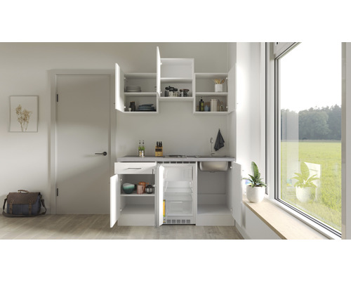 Compacte kitchenette met spoelbak, kookplaat, koelkast en hangkasten in een lichte ruimte.