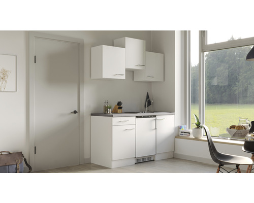 Kleine keuken met witte kasten en uitzicht uit het raam.
