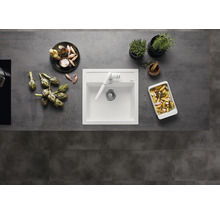 Keuken spoelbak met kraan, omringd door artisjokken, kruiden en bereide gerechten op een aanrecht.