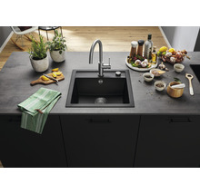 Zwarte gootsteen met kraan en diverse keukengerei op een aanrechtblad