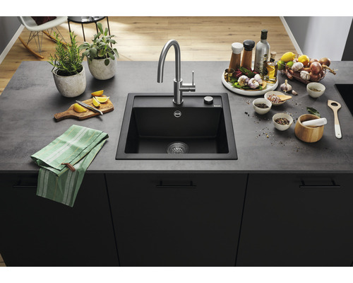 Zwarte gootsteen met kraan en diverse keukengerei op een aanrechtblad