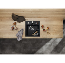 Zwarte gootsteen met kraan, zeepdispenser en hoekbak op een aanrecht