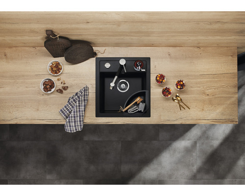 Zwarte gootsteen met kraan, zeepdispenser en hoekbak op een aanrecht