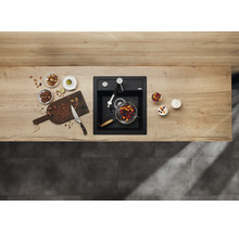 Keukenscène met spoelbak, kraan, snijplank en ingrediënten op een aanrecht.