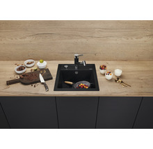 Keuken spoelbak van zwart materiaal met kraan op een werkblad met levensmiddelen