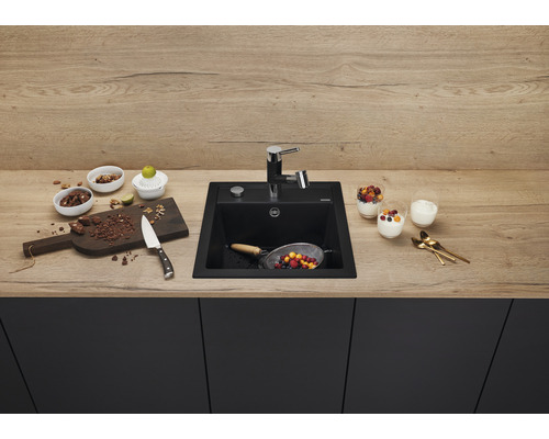 Keuken spoelbak van zwart materiaal met kraan op een werkblad met levensmiddelen