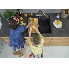 Twee kinderen bereiden in een keuken met spoelbak citroensap op een houten plank.