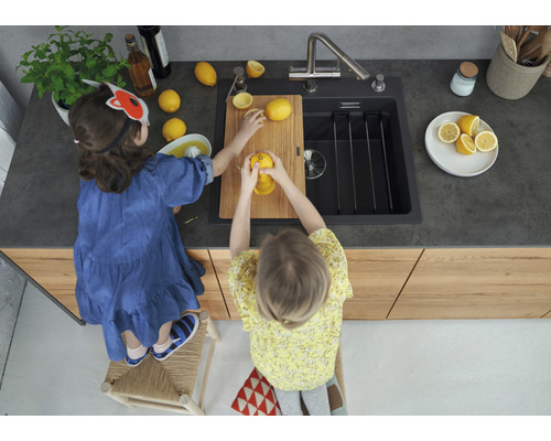 Twee kinderen bereiden in een keuken met spoelbak citroensap op een houten plank.