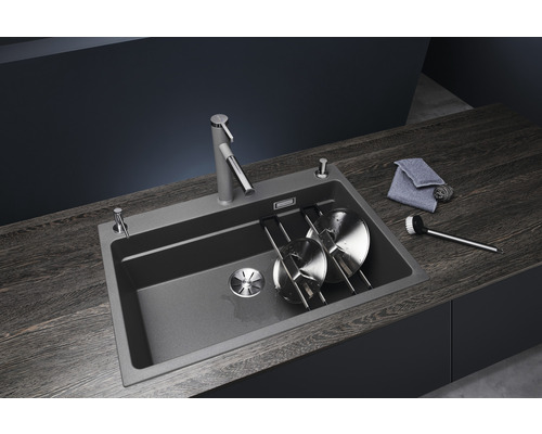 Spoelbak met kraan, zeepdispenser, afdruiprek, vaatdoek en afwasborstel op een donker werkblad