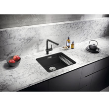 Zwarte gootsteen met kraan op marmeren aanrecht in een keuken.