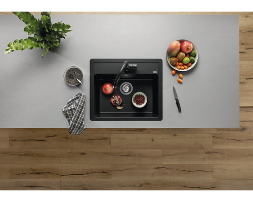 Bovenaanzicht van een spoelbak met kraan en fruitschaal op een werkblad.