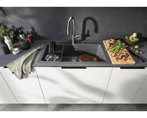 Keuken spoelbak met kraan, afdruiprek en verse ingrediënten op het aanrecht.