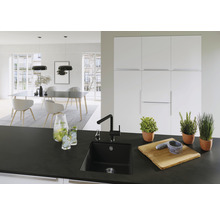 Moderne keuken met zwarte spoelbak, kraan en houten accessoires op het aanrecht.