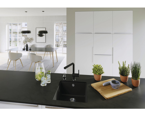 Moderne keuken met zwarte spoelbak, kraan en houten accessoires op het aanrecht.