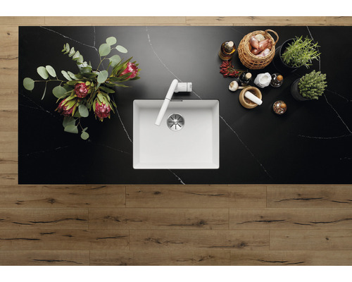 Bovenaanzicht van een keuken met een spoelbak, kraan, bloemen, kruiden en specerijen op een werkblad