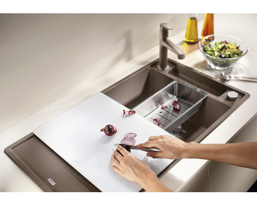 Spoelbak met snijplank, afdruipbak, kraan en persoon die uien snijdt