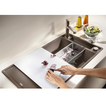 Keukenspoelbak met snijplank, afdruipbak, armatuur en persoon die een ui snijdt