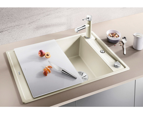 Keuken spoelbak met kraan, snijplank, mes en fruit.