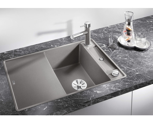 Spoelbak met afdruiprek, kraan en zeepdispenser op donker aanrechtblad