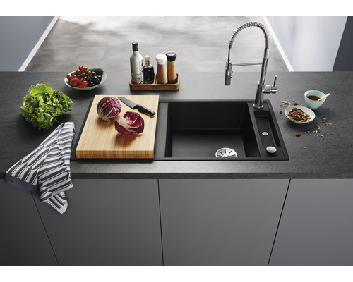 Keukenspoelbak met kraan, snijplank en voedsel op een aanrecht.