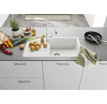 Keuken spoelbak met kraan, omgeven door groenten en keukengerei.