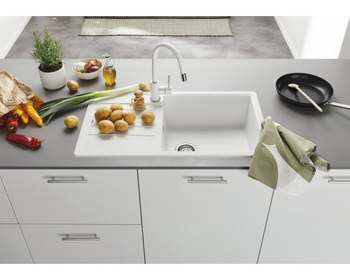 Keuken spoelbak met kraan, omgeven door groenten en keukengerei.