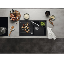 Keuken spoelbak met afdruiprek, kraan en levensmiddelen op een werkblad.