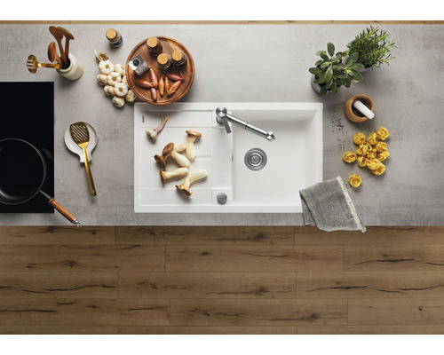 Keukenscène met spoelbak, kraan, kookgerei en voedingsmiddelen op een werkblad.