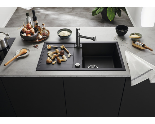 Keuken spoelbak met afdruiprek, kraan en etenswaren op het aanrecht.