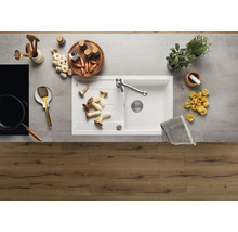 Spoelbak met kraan, omringd door voedsel en keukengerei op een aanrecht