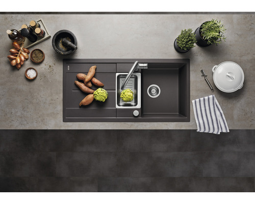 Spoelbak met afdruiprek, kraan, groenten en keukengerei op een aanrecht