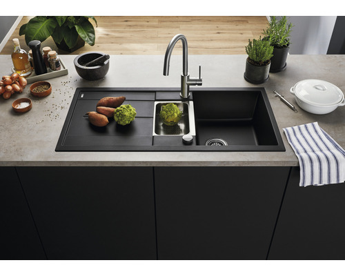 Spoelbak van zwart materiaal met afdruiprek, kraan en groenten