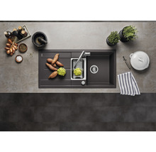 Spoelbak met afdruiprek, kraan, groentesnijder en ingrediënten op een aanrecht.