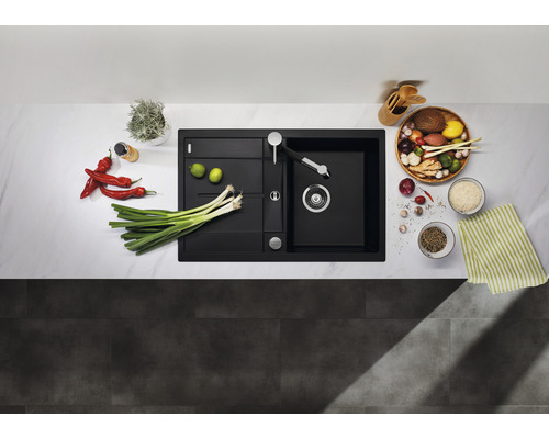 Zwarte gootsteen met afdruiprek en kraan op een aanrecht met groenten