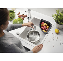 Vrouw vult pan met water in een wasbak met groenten en aardappelen