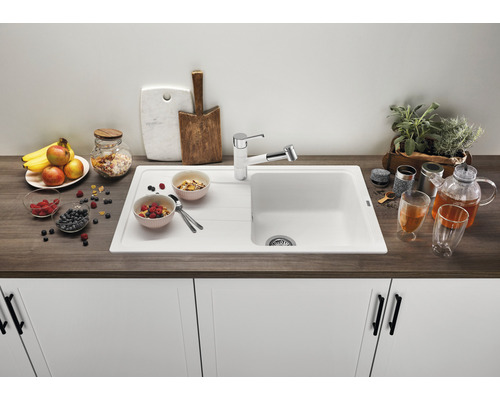 Keuken spoelbak met afdruiprek, kraan en decoratieve levensmiddelen op een aanrecht