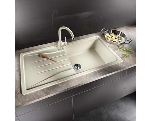 Beige gootsteen met afdruiprek en bijpassende kraan op een aanrecht.