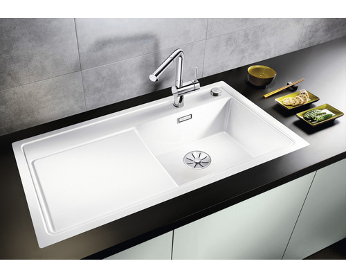 Witte gootsteen met afdruiprek en kraan op een donker aanrechtblad