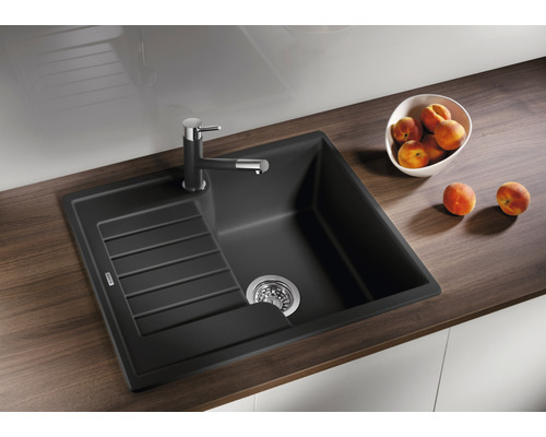 Zwarte composiet spoelbak met afdruiprek en kraan op een aanrecht met perziken.