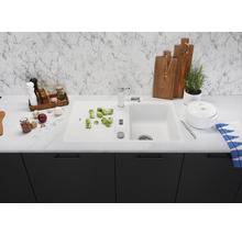 Keuken spoelbak met kraan, groenten en keukengerei op een aanrecht.