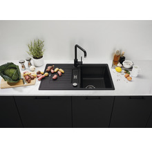 Zwarte aanrechtgootsteen met afdruiprek en kraan op een aanrecht met voedingsmiddelen