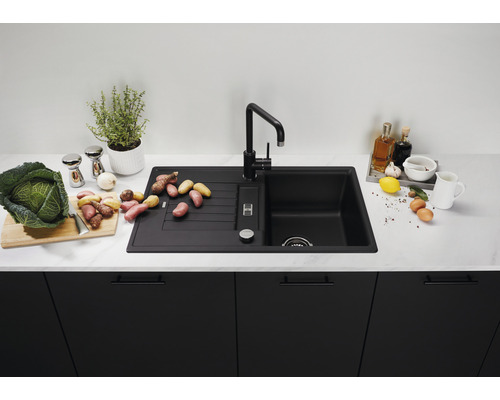 Zwarte gootsteen met afdruiprek en kraan op een aanrecht met voedingsmiddelen