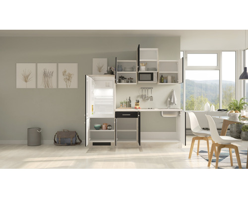 Compacte kitchenette met spoelbak, koelkast, hangkasten en eettafel in een lichte ruimte