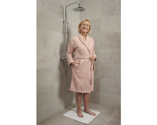 Vrouw in badjas onder een douche met antislipmat